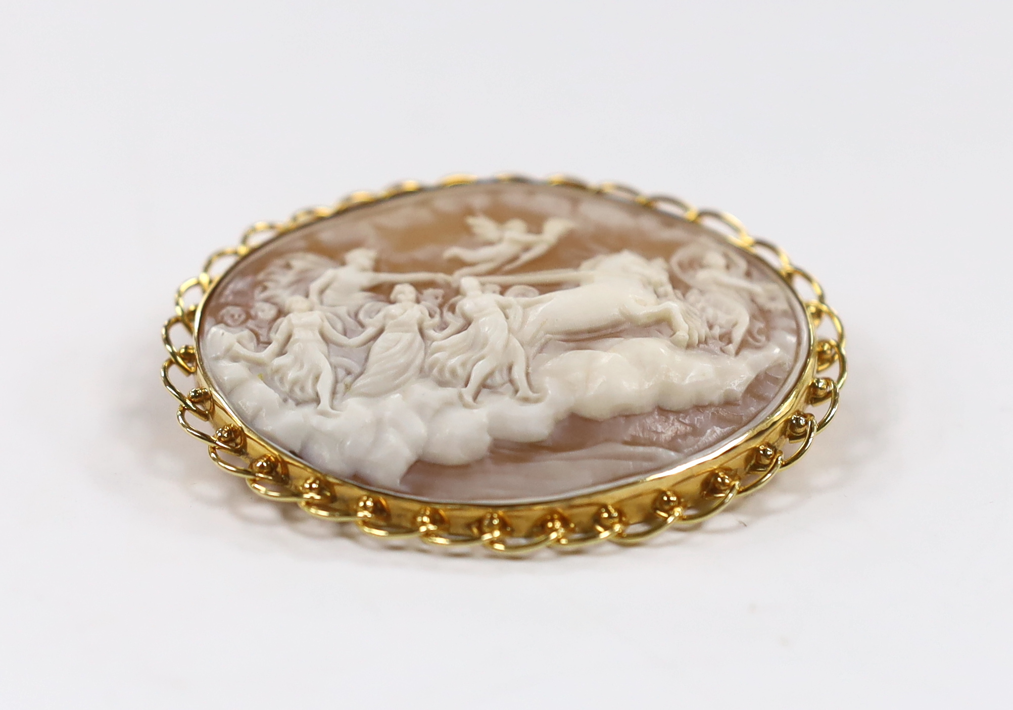 A modern 18k mounted oval cameo shell pendant brooch, carved with Phoebus and the hours preceded by Aurora, 58mm, gross weight 16 grams.